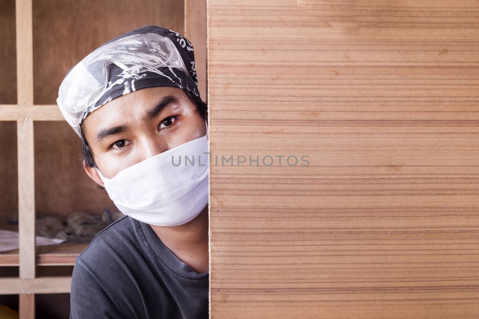 Young male carpenter and wood background