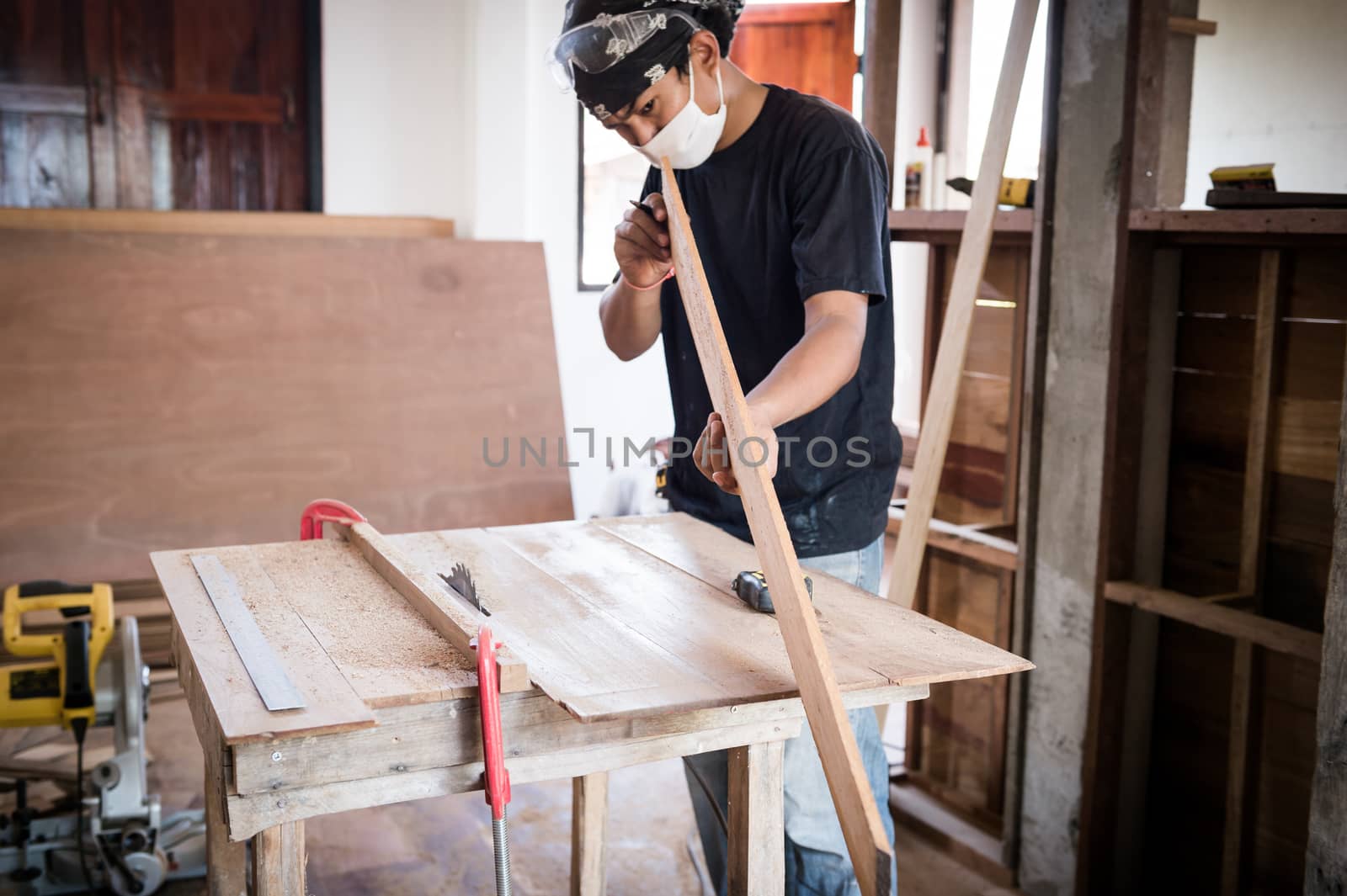 Young male carpenter working with wood in workshop