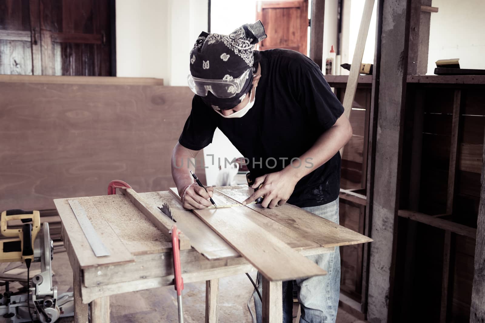 Young male carpenter working with wood in workshop by sayhmog