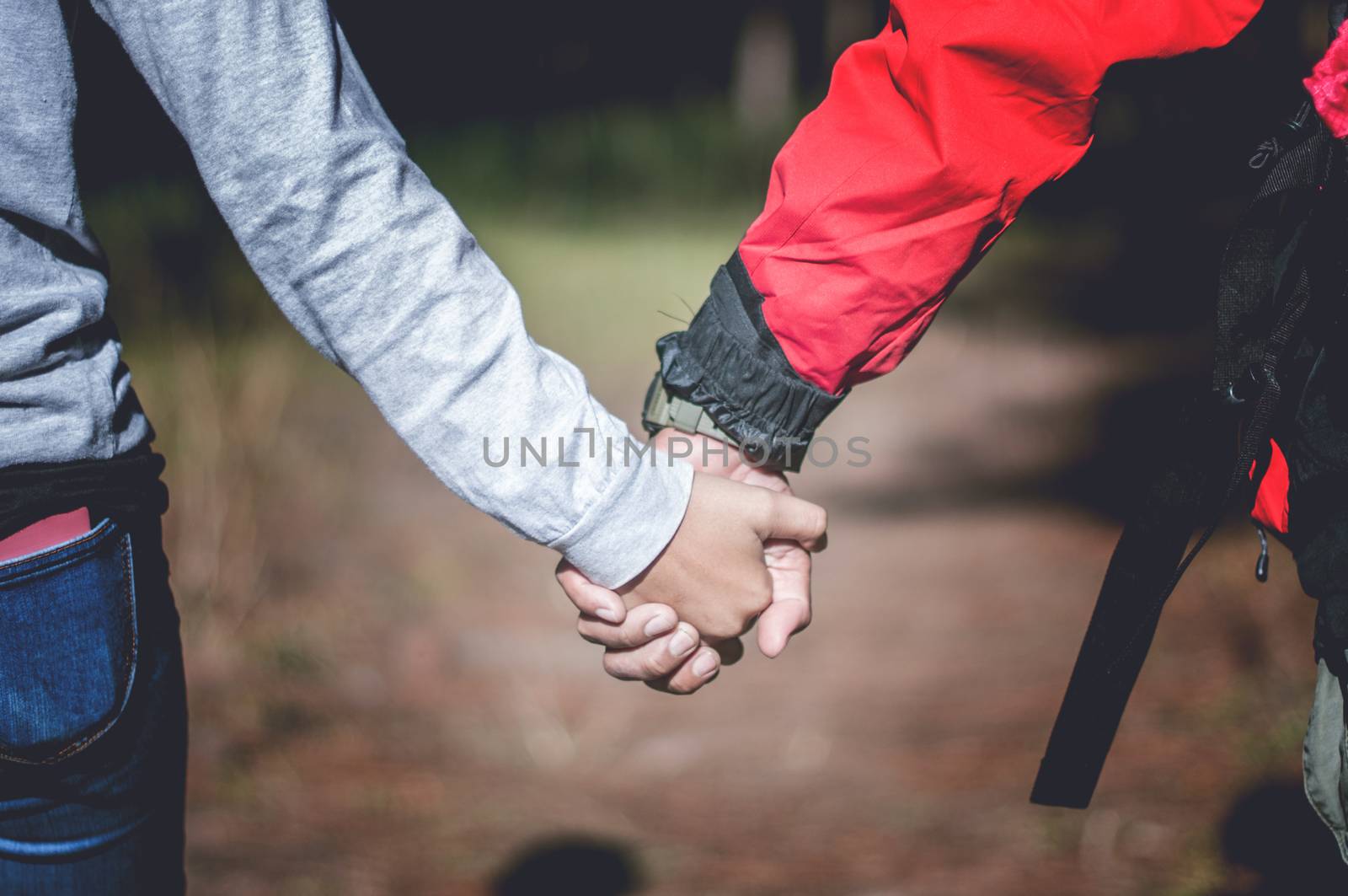 Young couple holding hands in forest, traveling concept