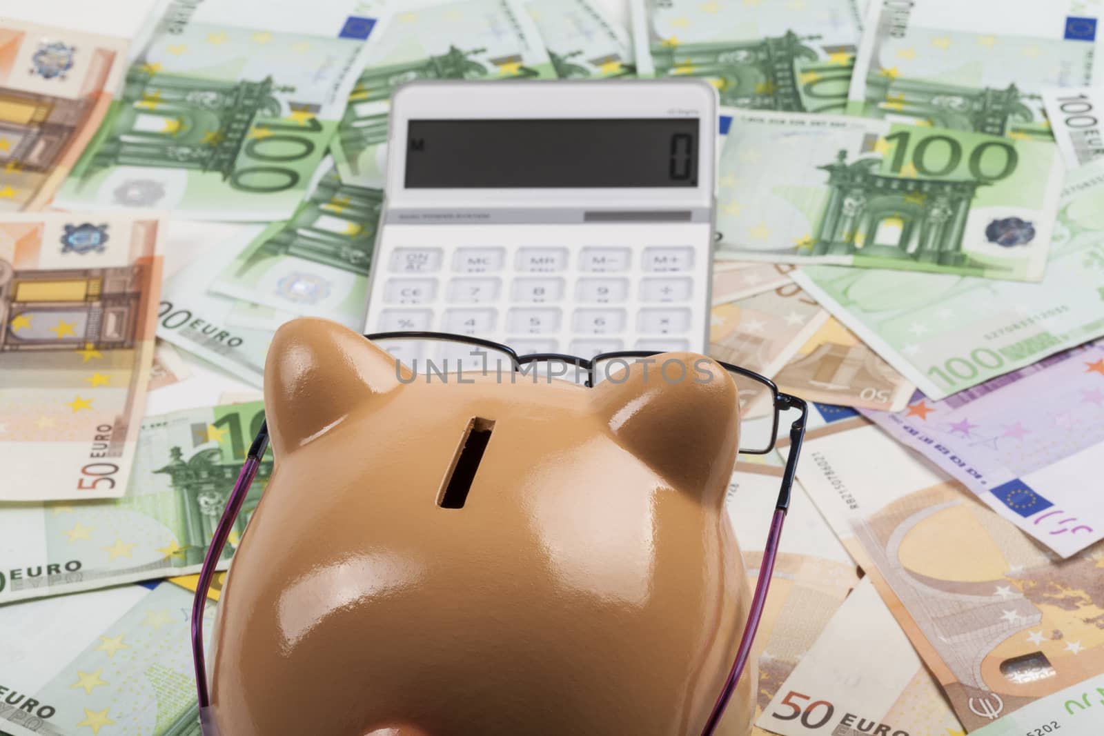 Piggy Bank on Euro Banknotes With White Calculator. European Expences Costs