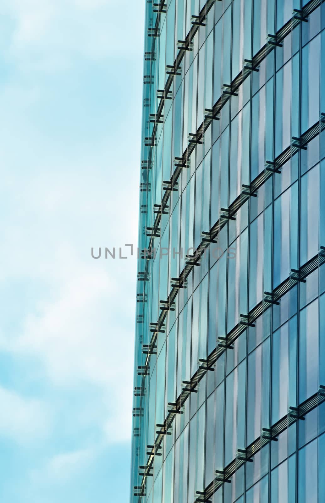 Background texture of modern business skyscraper building glass windows pattern with reflection over cloudy blue sky, low angle view