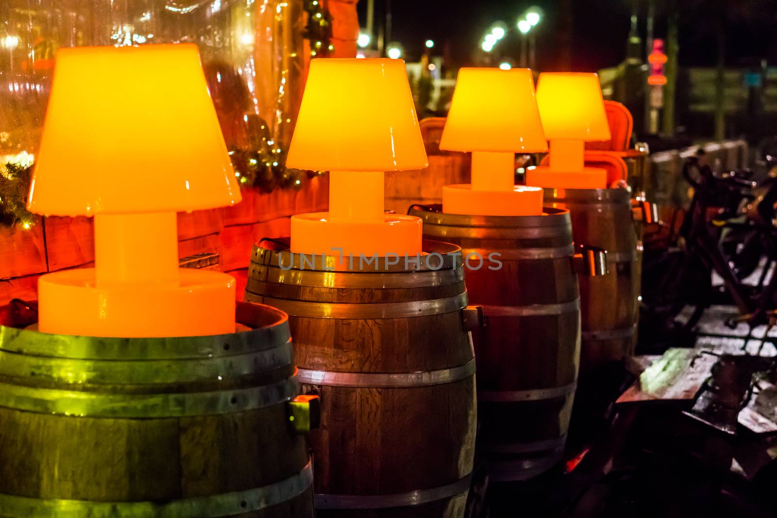 outdoor bar decoration background, line of illuminated red lamps standing on wooden barrels