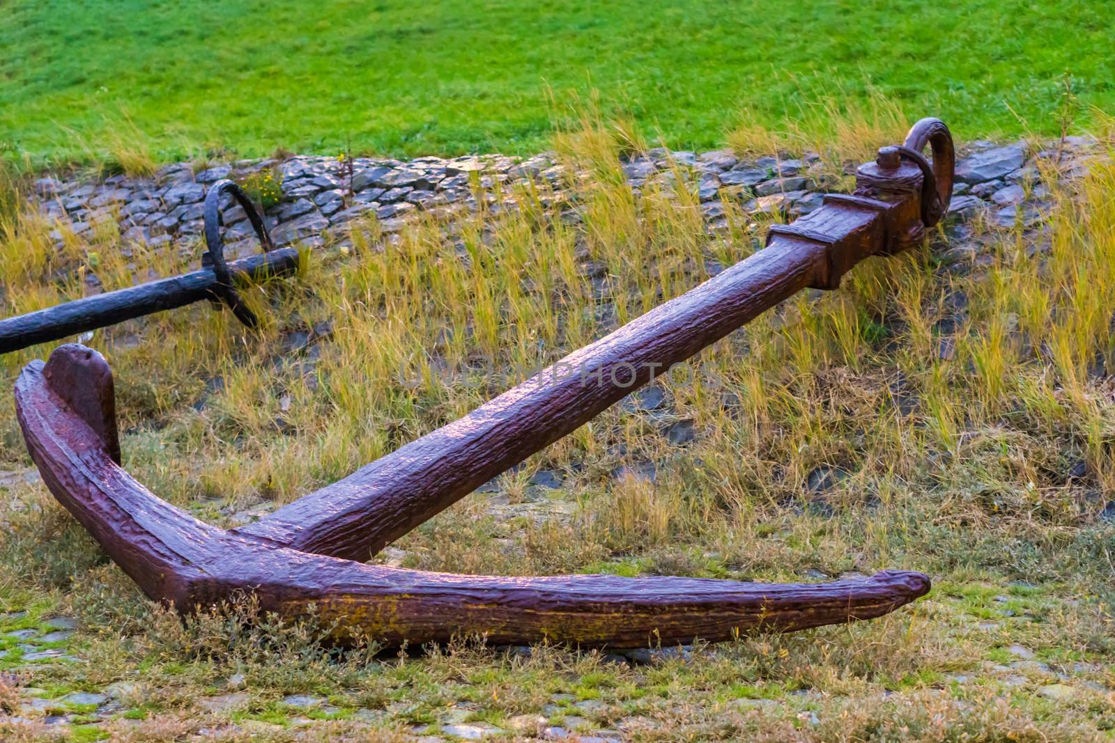 Big old rusty pirate ship anchor laying on the ground, harbor decoration background