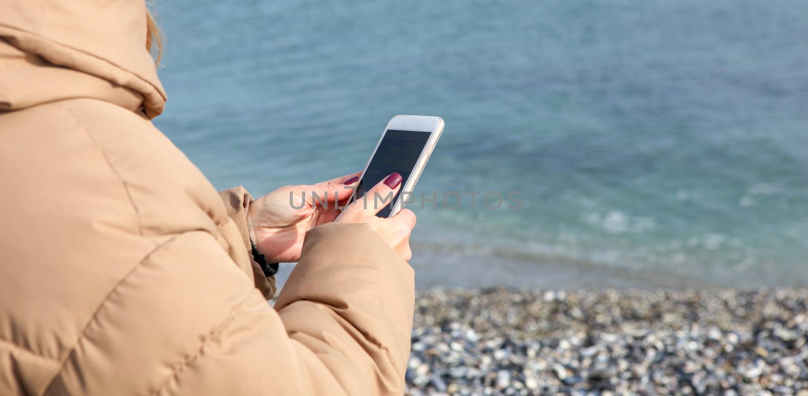 Beautiful Woman Using Smart Phone On A Beach by nenovbrothers