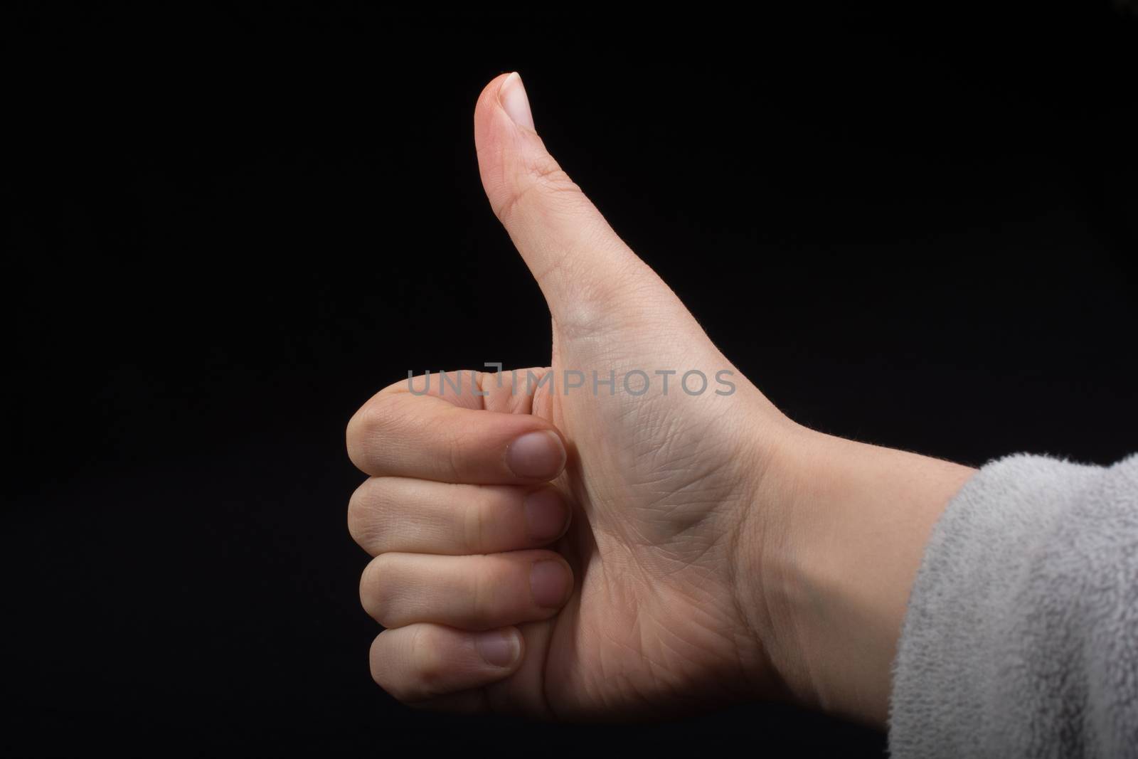 Young hand with thumb up  on black background