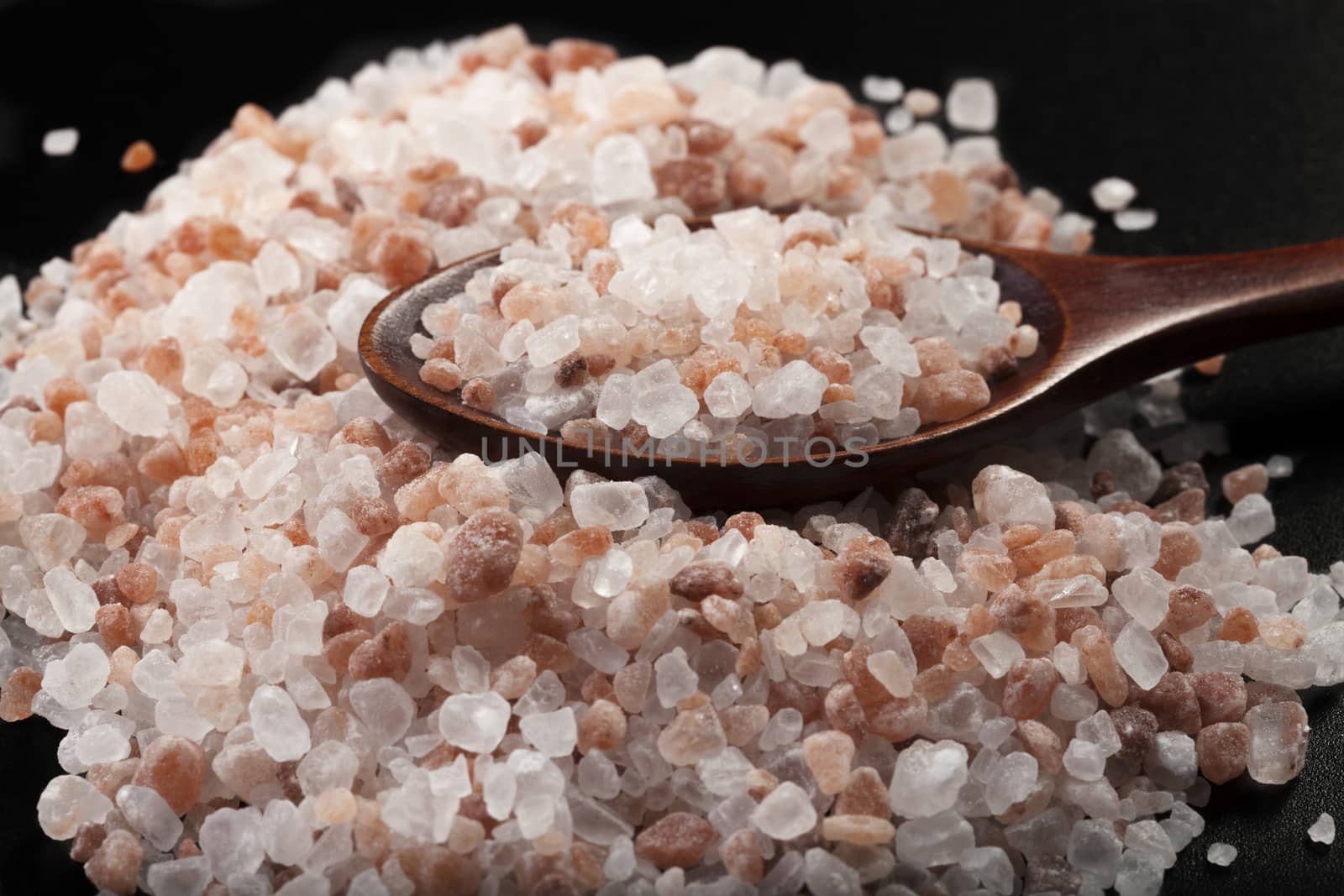 Himalayan Salt Pile With Wood Spoon Close-up on Black Background