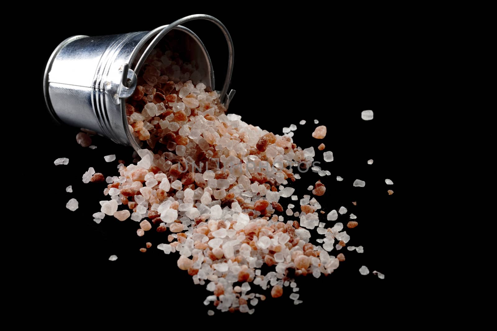 Spilled Himalayan Salt From Silver Metal Bucket on Black Background
