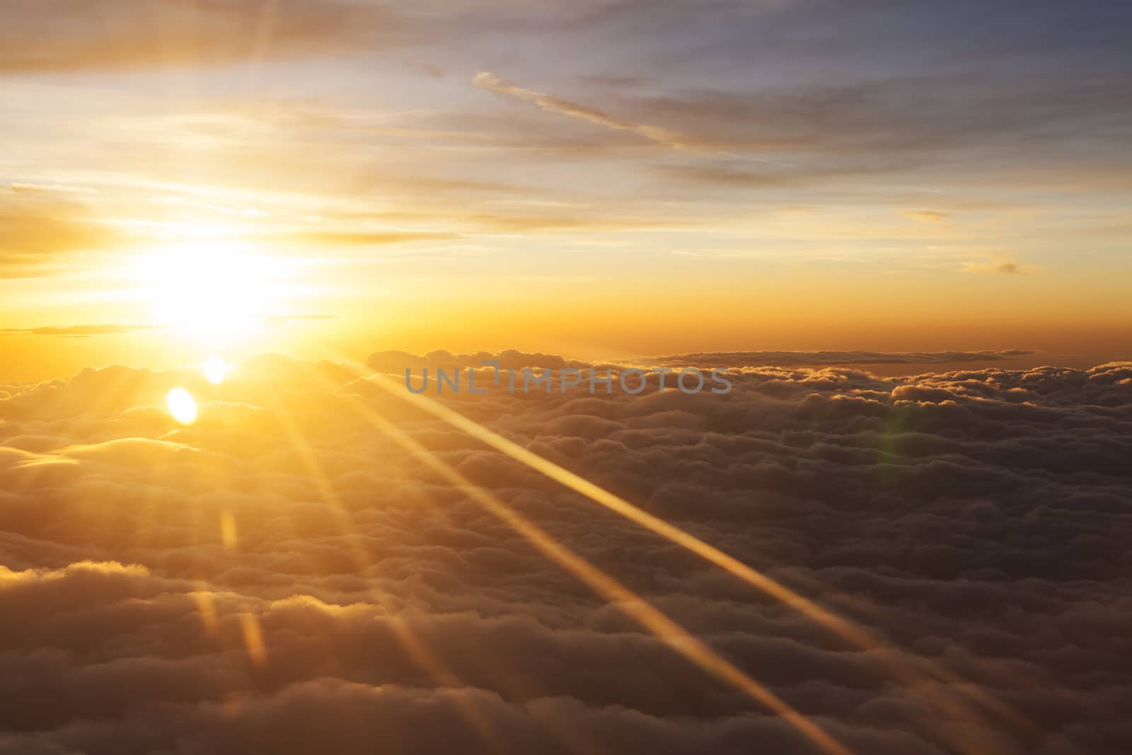 Sunrise over fluffy clouds with bright rays of light