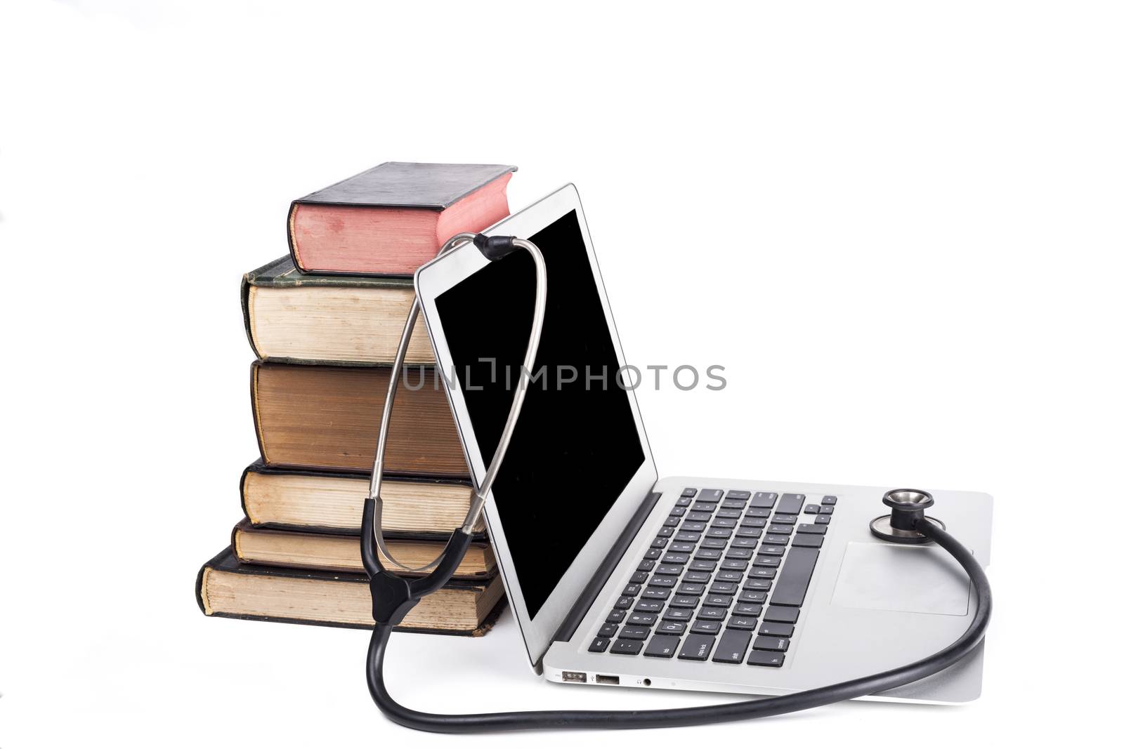 Silver laptop with black stethoscope and old books pile isolated on white background