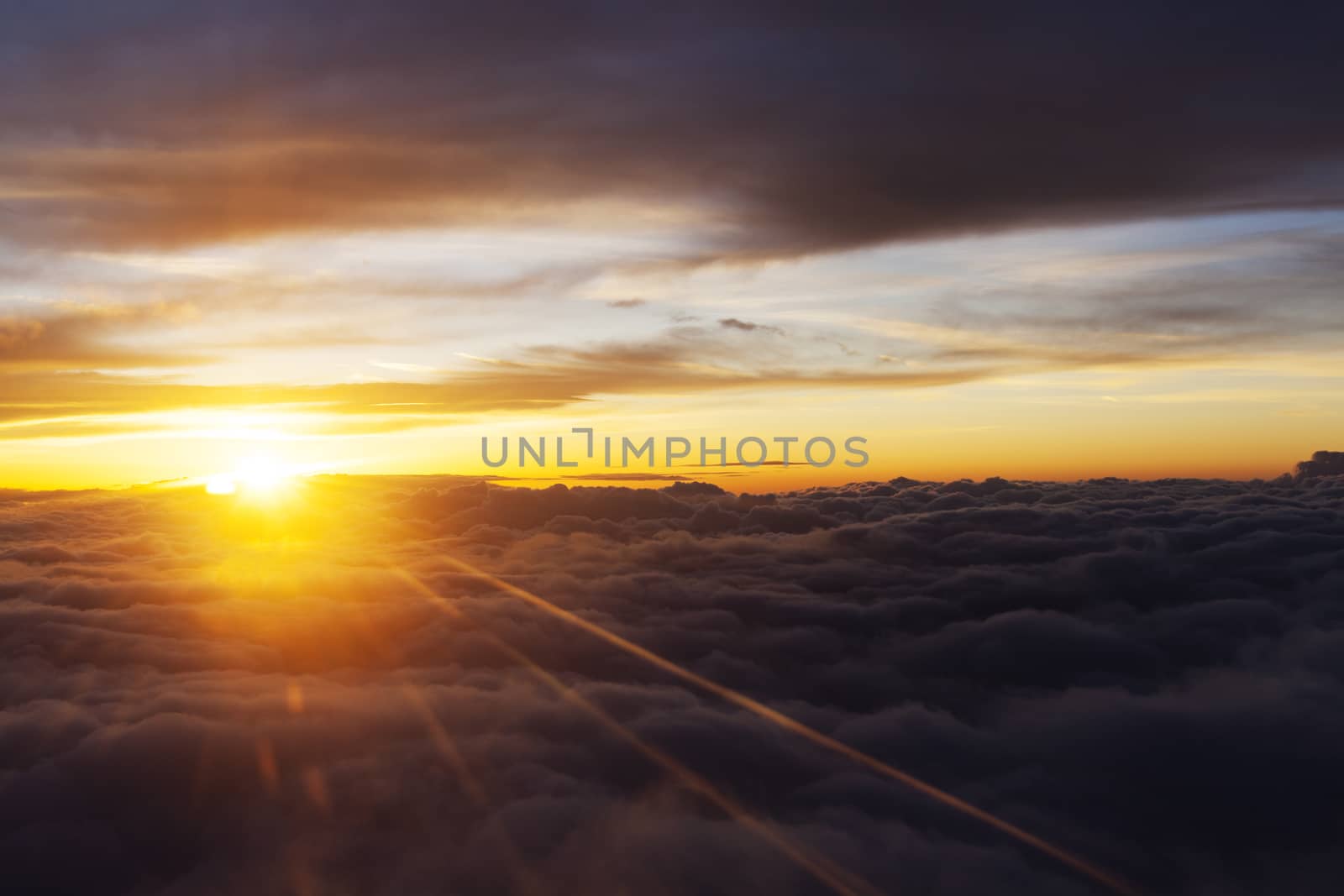 Sunrise over fluffy clouds with bright rays of light