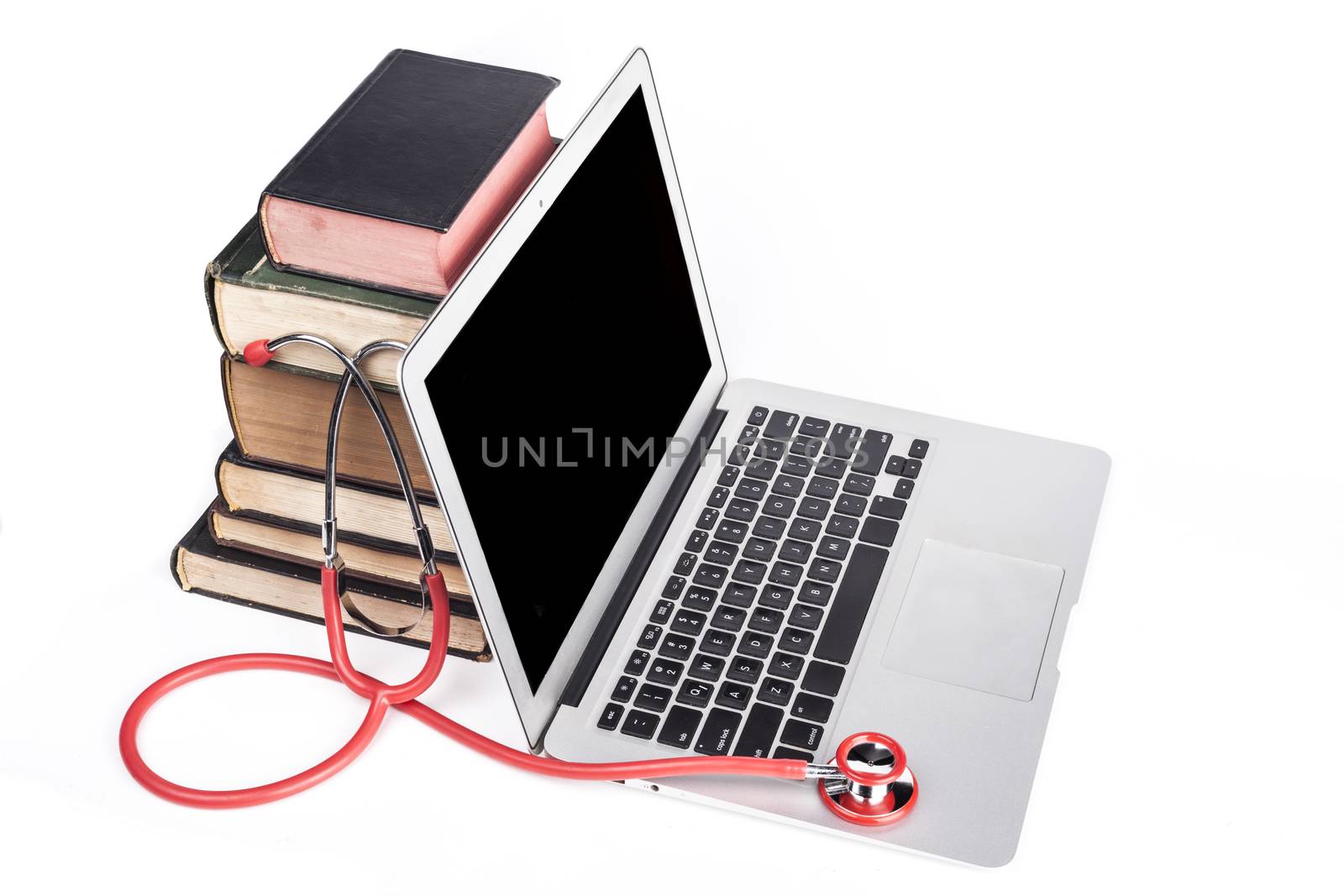 Silver laptop with red stethoscope and old books pile isolated on white background