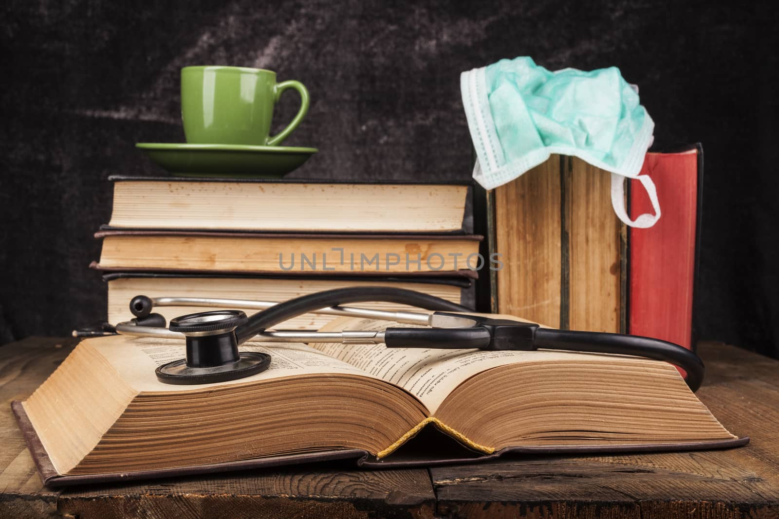 Stethoscope on open book and coffee on books pile
