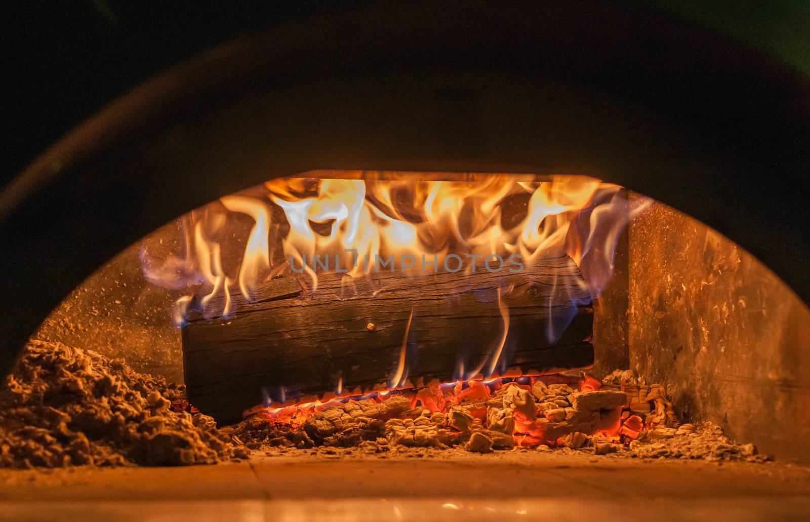 wood burns in pizza oven close up on flames and burning embers
