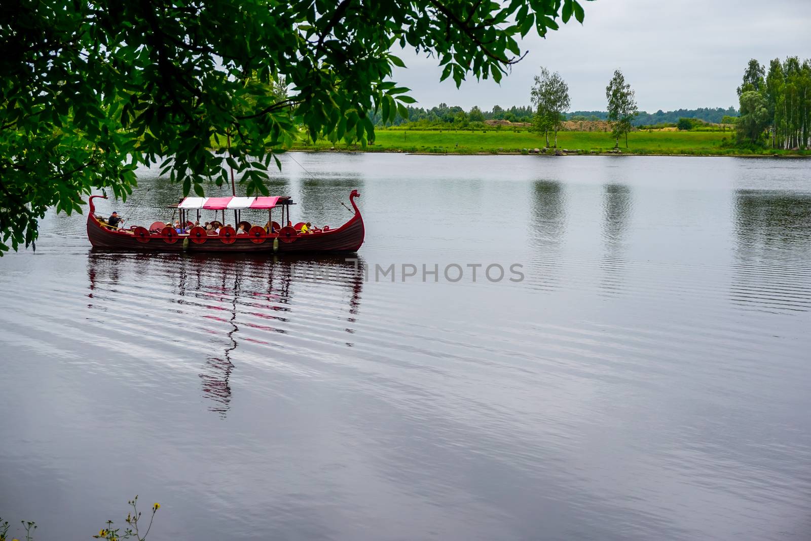 Tourist boat in the style of viking on river Daugava, Latvia. Ancient boat in Daugava river at Koknese. Old wooden viking boat in river Daugava, Latvia.