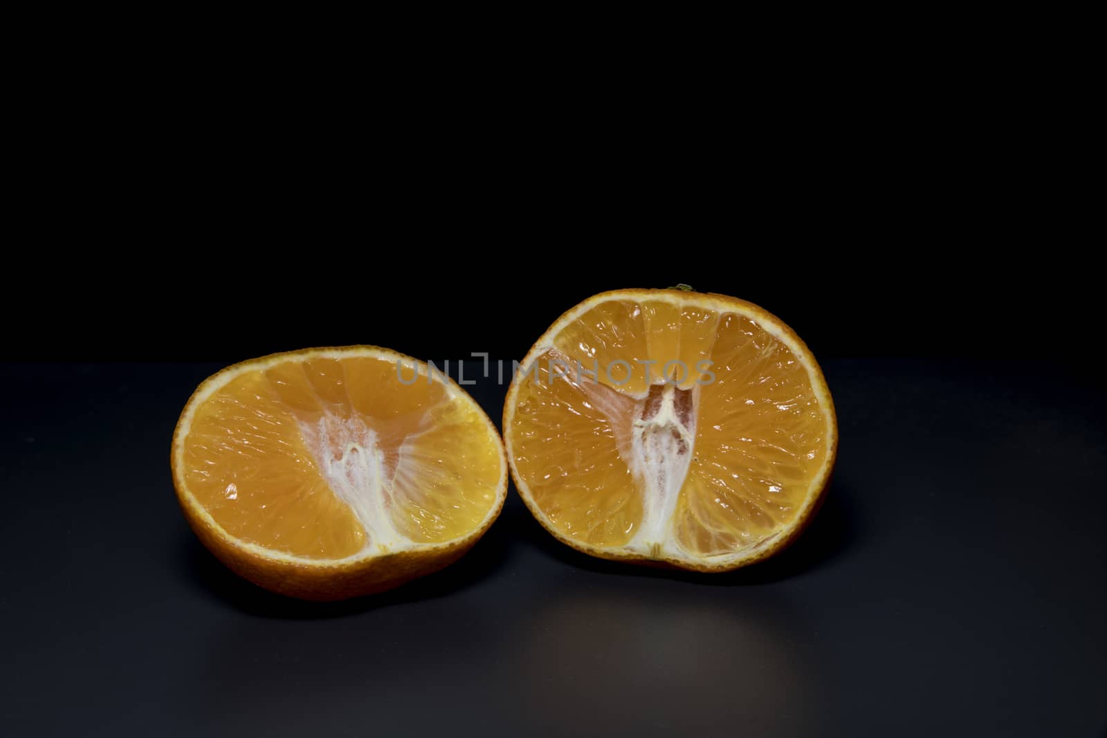 orange in two cut pieces on black background  by compuinfoto