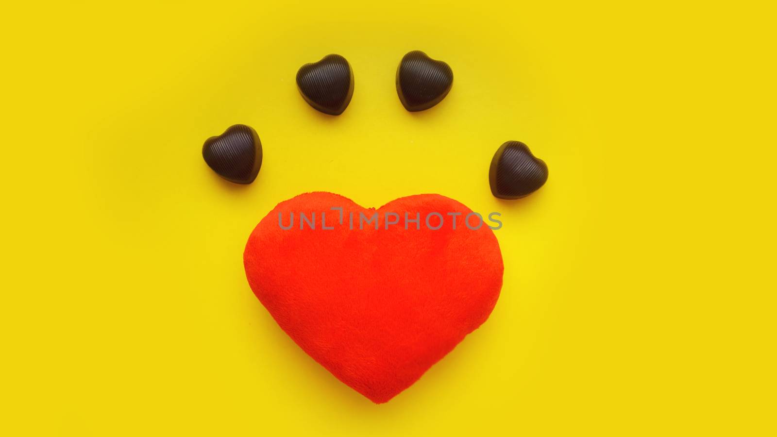 Valentines day background with soft toy heart and chocolates on yellow background. Top view. For banner, cards design