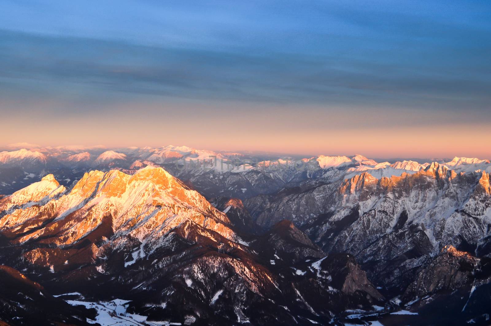 Panoramic aerial viewf of Alpine peaks over Austria in sunset, flying above the Alps, travel and landscape concept, winter tourism in Europe
