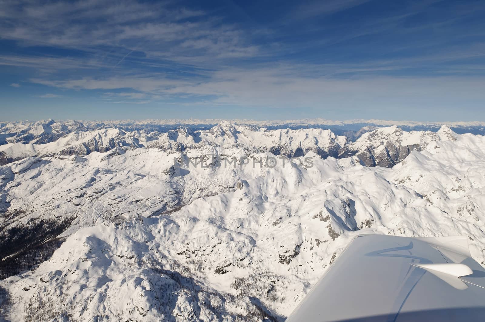 Flying above Mount Triglav in Julian Alps in winter, aerial landscape panorama of mountains covered with snow, highest mountain in Slovenia, Austrian Alps in background