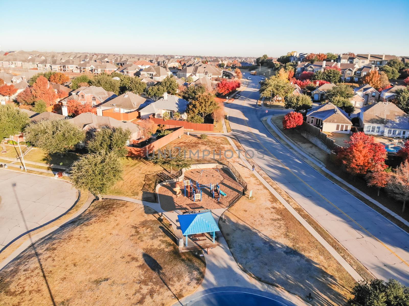 Aerial view small neighborhood playground in residential community near Dallas, Texas, USA. Row of single-family detached houses with garden and colorful autumn leaves