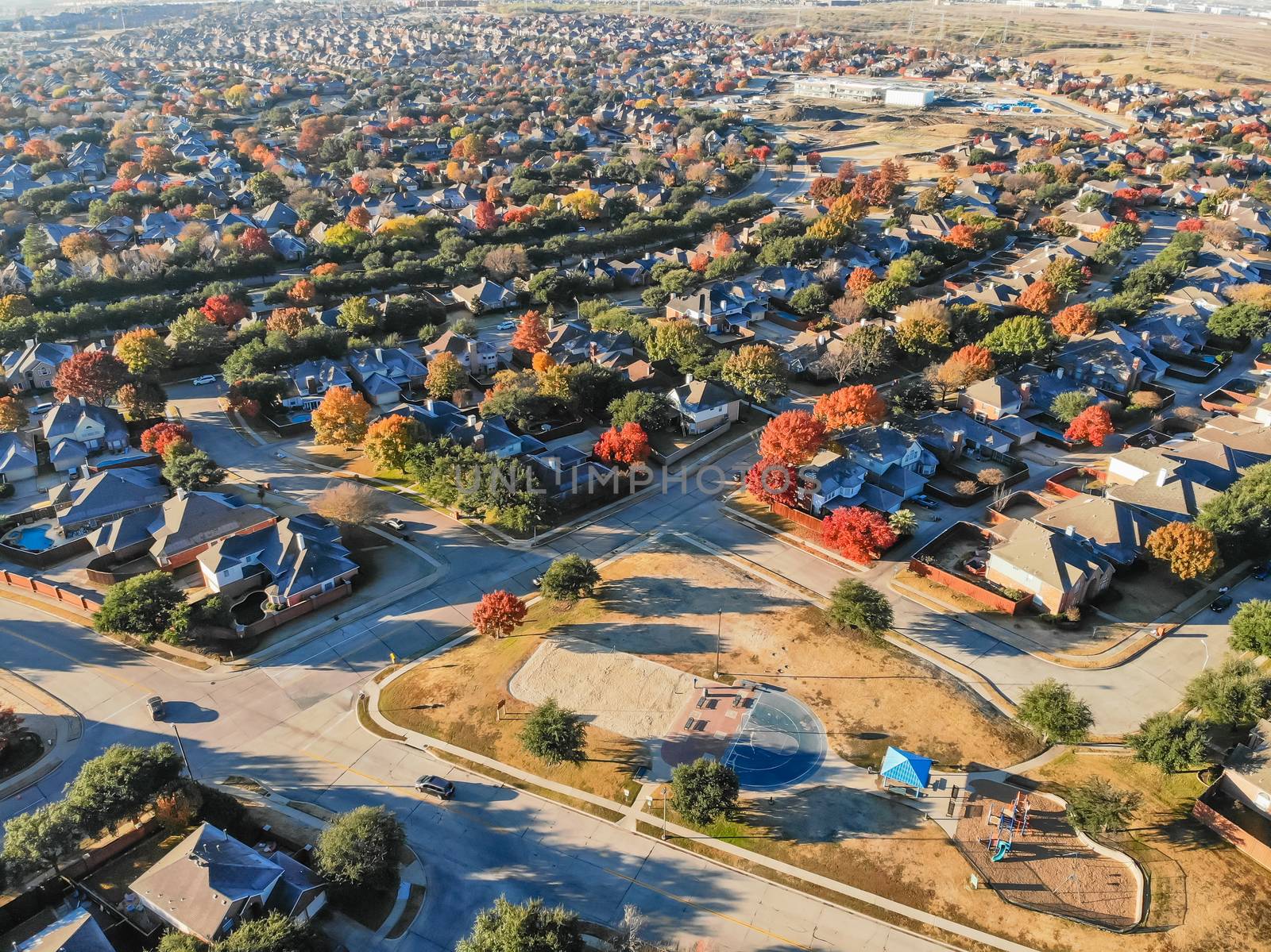 Top view community playground near residential area with row of single-family detached house and colorful autumn leaves. Urban sprawl subdivision in background