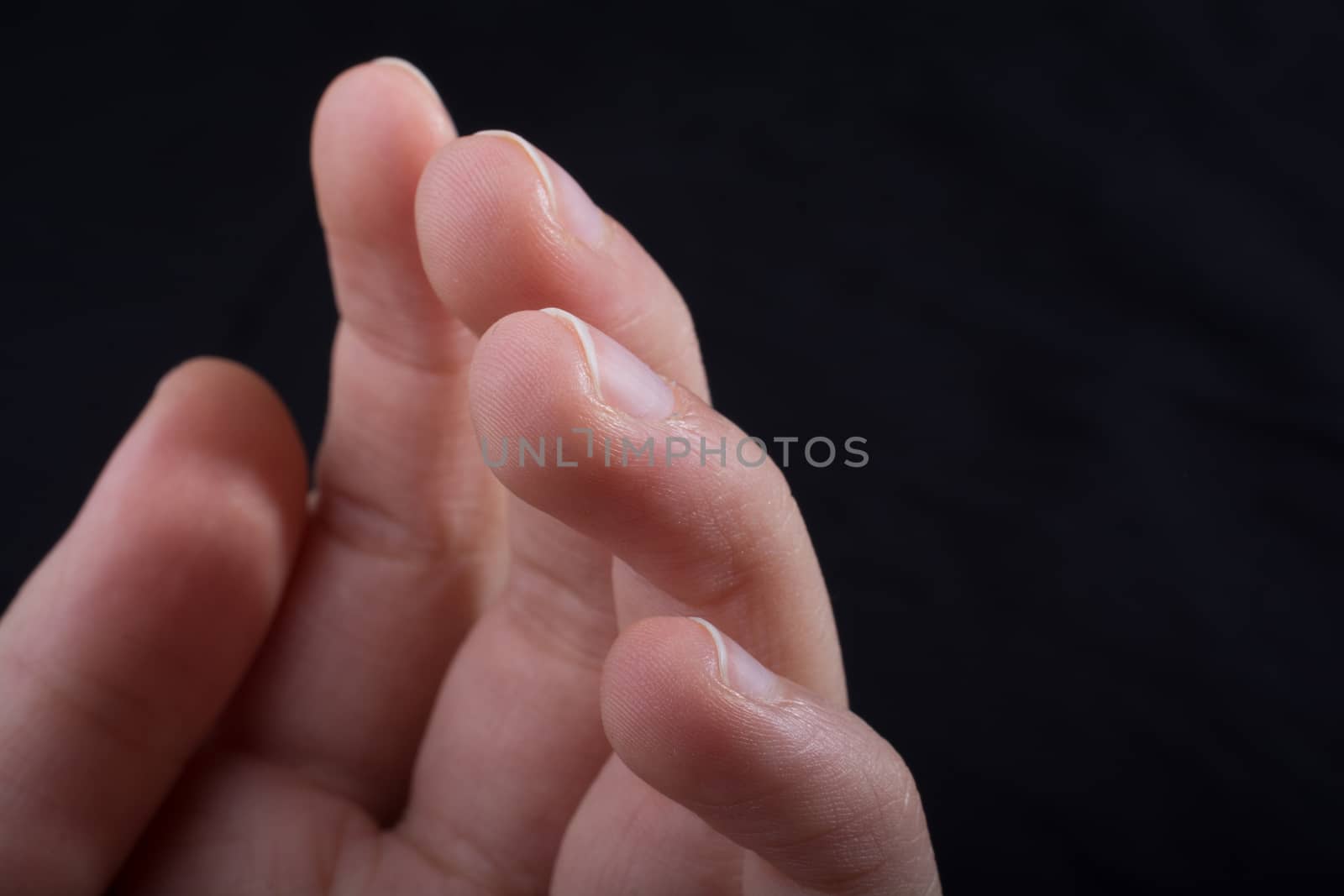 Five fingers of a child hand partly seen in black background