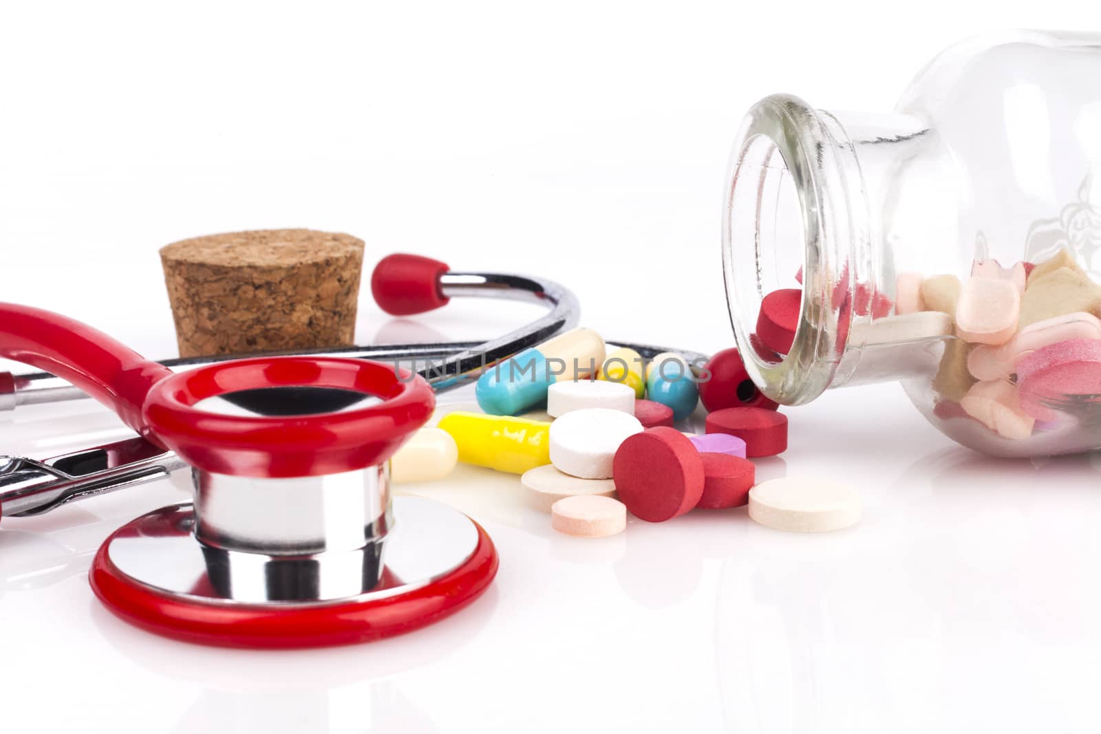 Red Stethoscope with jar of pills Close-up Isolated On White Background