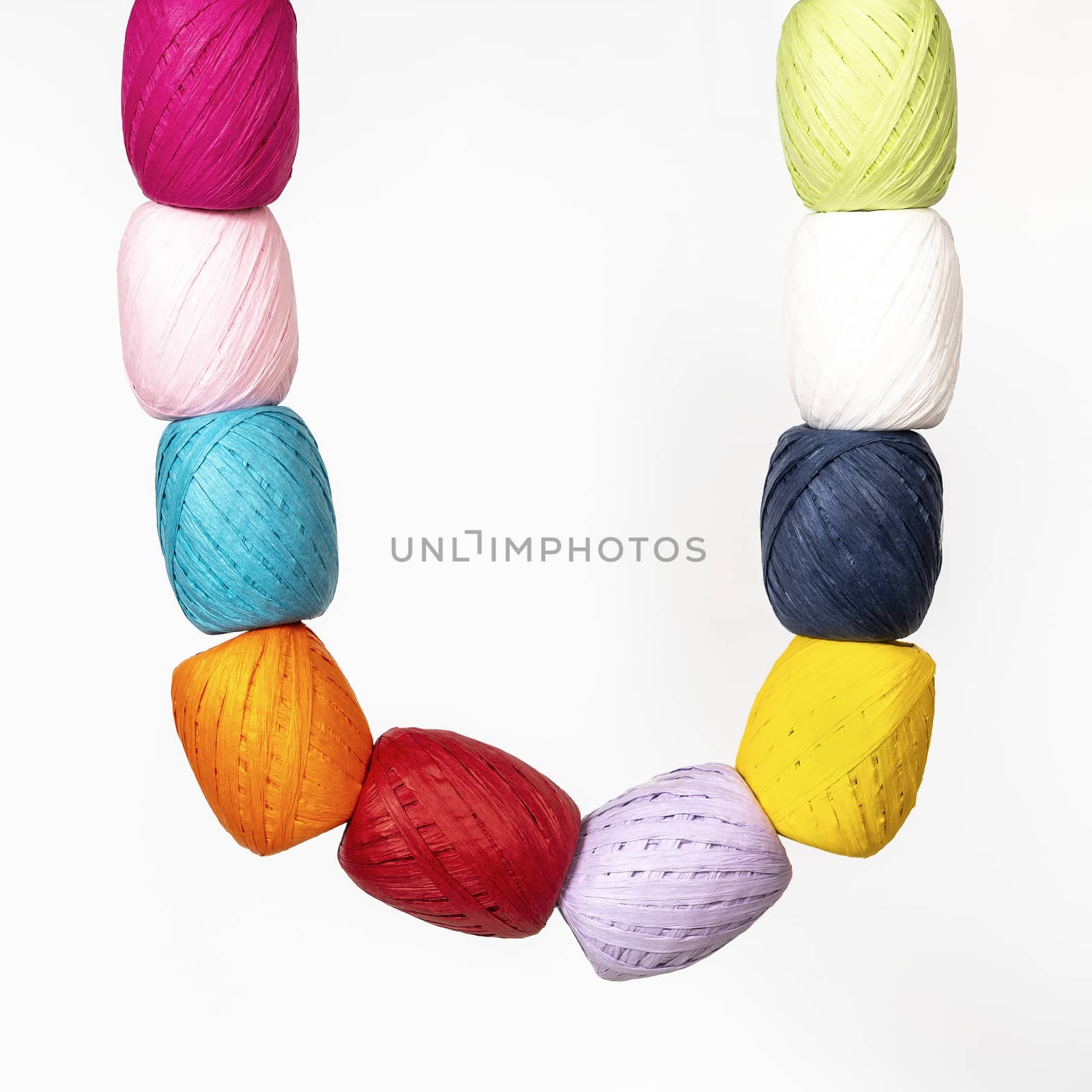 some colored raffia balls hanging from a white surface