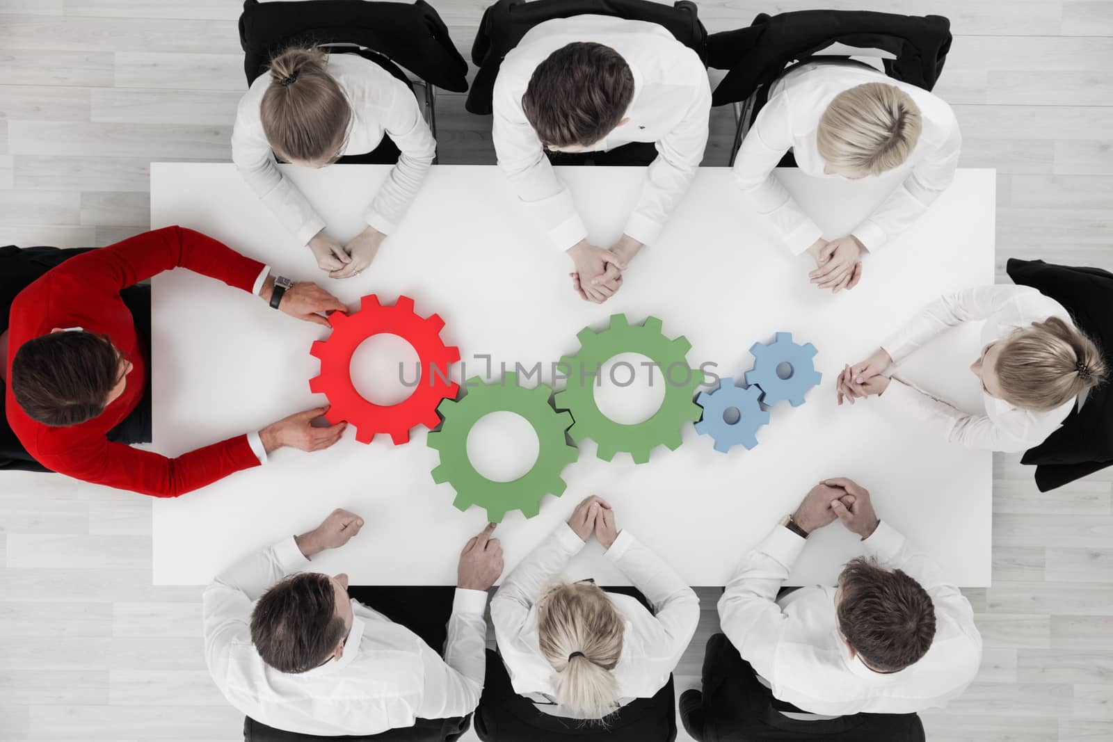 Conceptual image of businessteam working cohesively , colorful cogs on table, interaction and unity