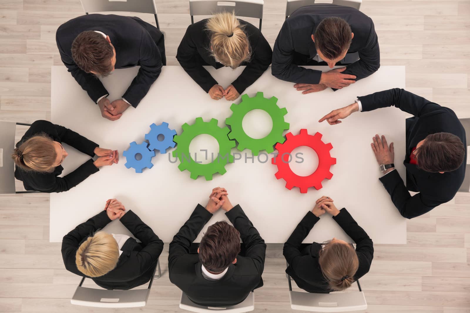 Conceptual image of businessteam working cohesively , colorful cogs on table, interaction and unity