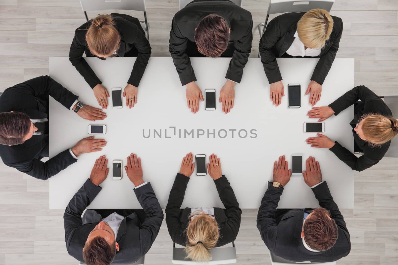 Business people not using smartphones sitting around white table