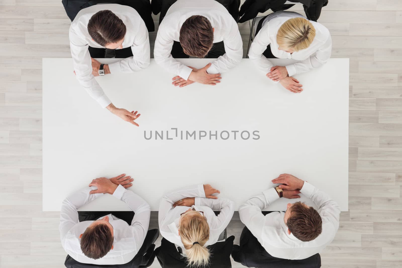 Business people sitting around empty table , copy space for text , business man pointing to blank copy space in the middle