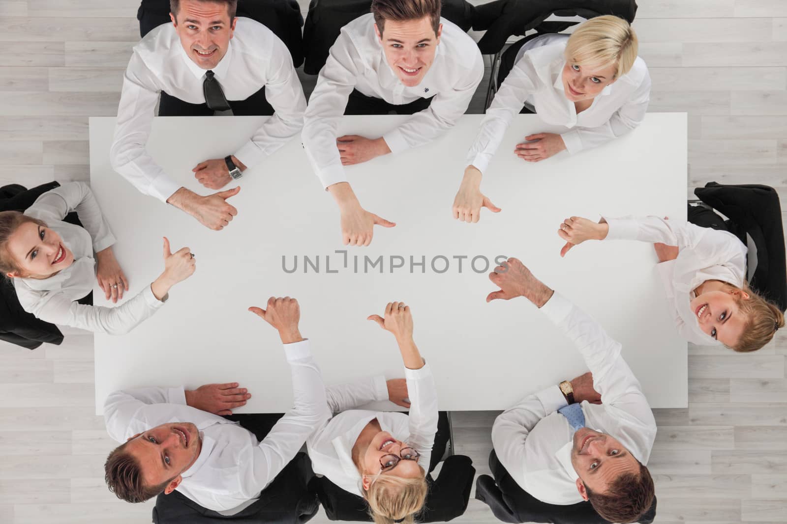 Business people team sitting around white table smiling and showing thumbs up