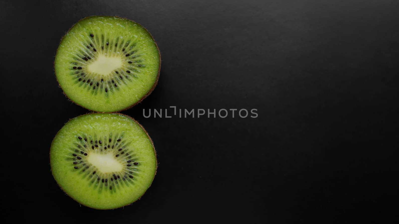Juicy green kiwi fruit on a black background, top view, copy space