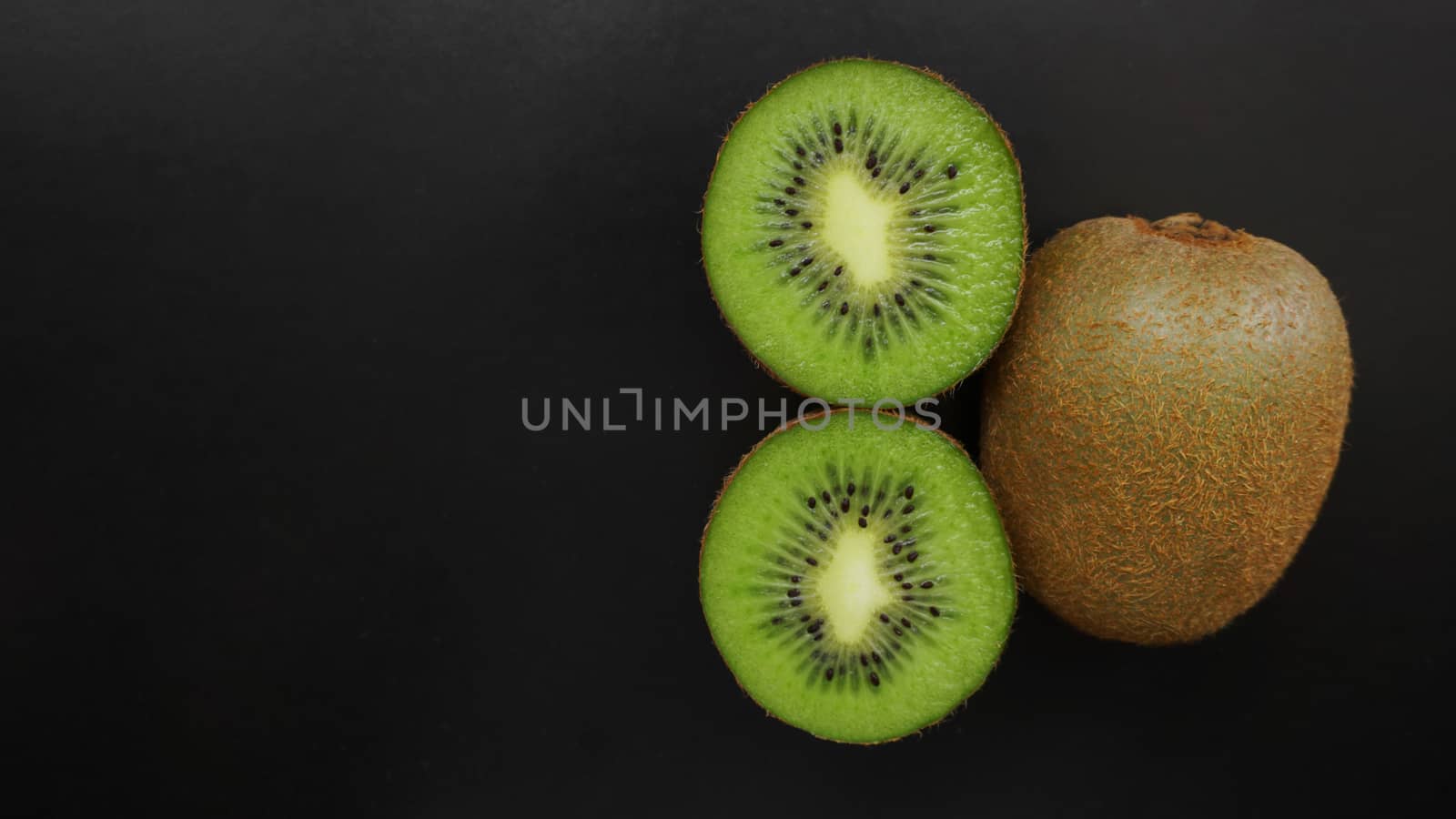 Juicy kiwi fruit on a black background, top view, copy space by natali_brill