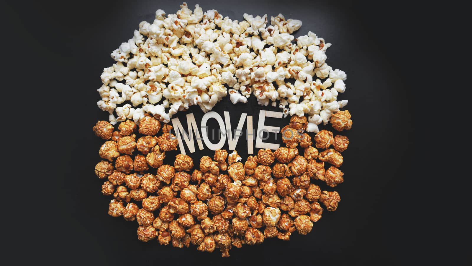 Popcorn on black background. Watching a movie with popcorn. Copy space. Pop corn. Top view. Flat lay. Wooden letters movie