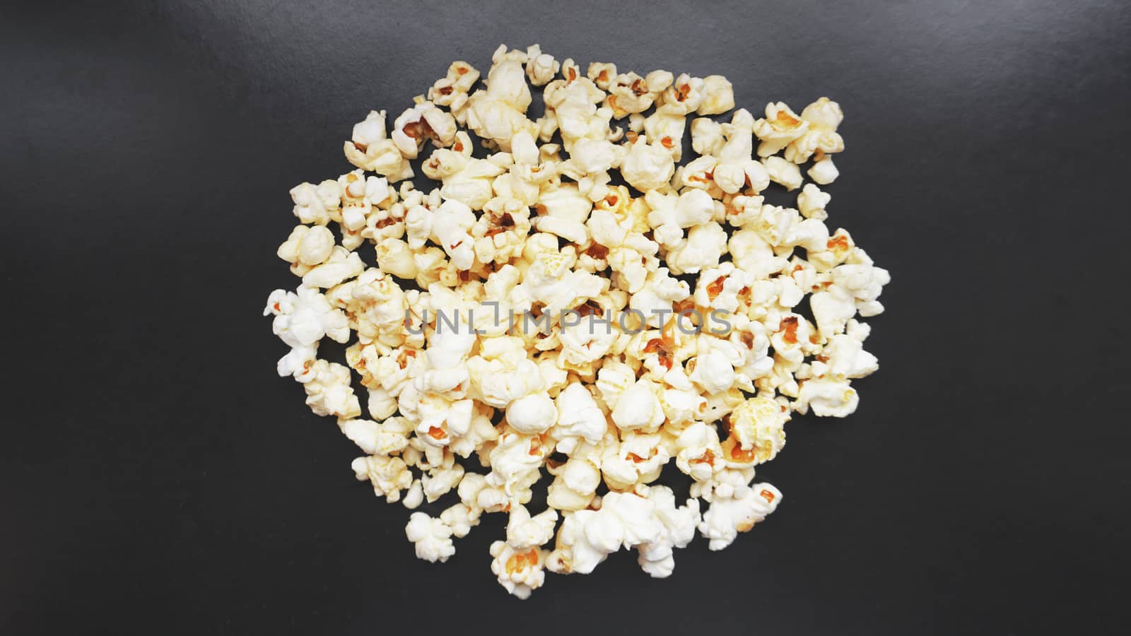 Heap of classic salty popcorn on black background. Concept cinema and entertainment