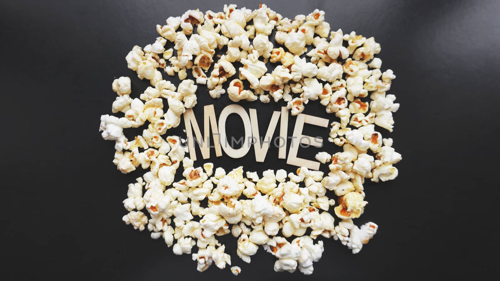 Popcorn on black background. Watching a movie with popcorn. Copy space. Pop corn. Top view. Flat lay. Wooden letters movie