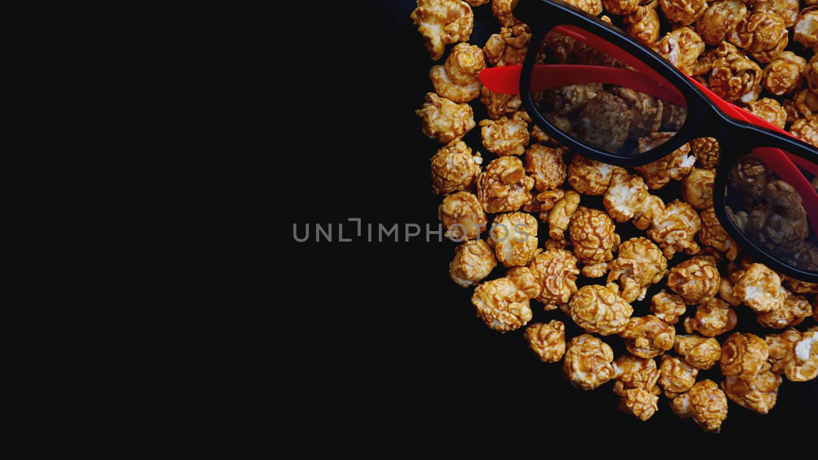 Abstract image of viewer, 3D glasses and popcorn on black background. Still life, top view, flat lay. Concept cinema and entertainment