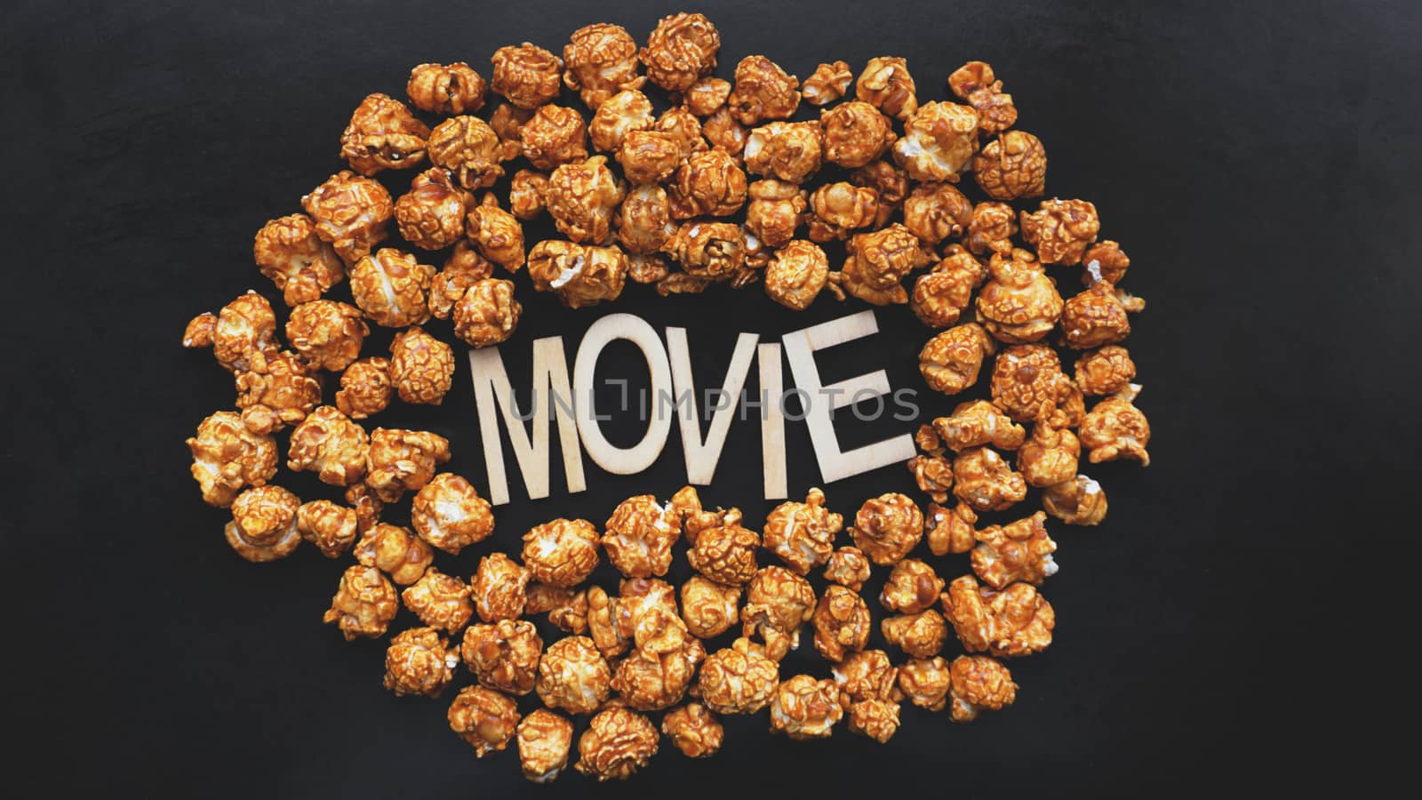 Golden caramel popcorn closeup. Background of popcorn. Wooden letters Movie by natali_brill