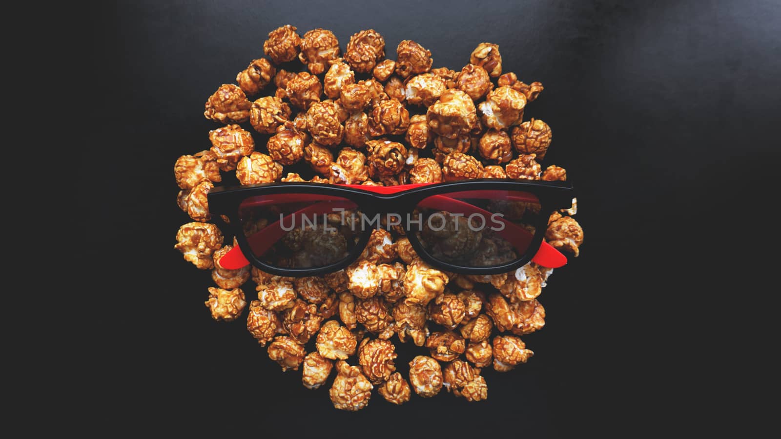 Abstract image of viewer, 3D glasses and popcorn on black background. Still life, top view, flat lay. Concept cinema and entertainment