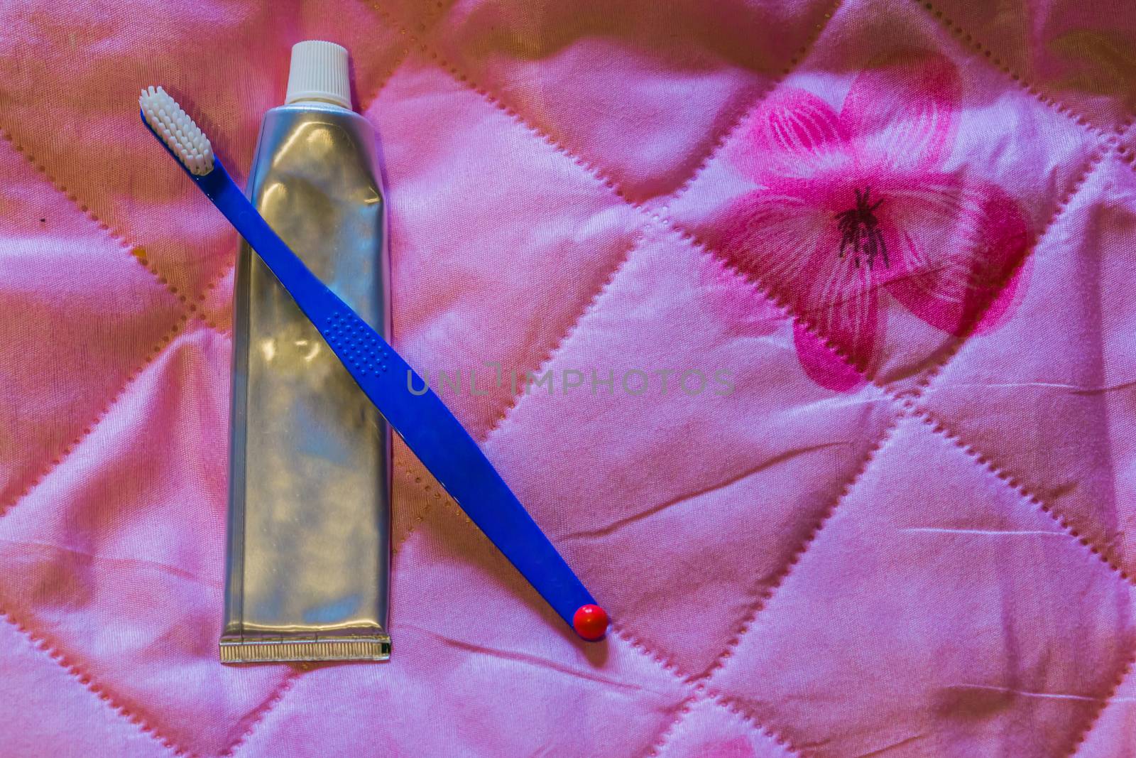 simple tooth brush with a silver blank tube of tooth paste, isolated on a pink background by charlottebleijenberg