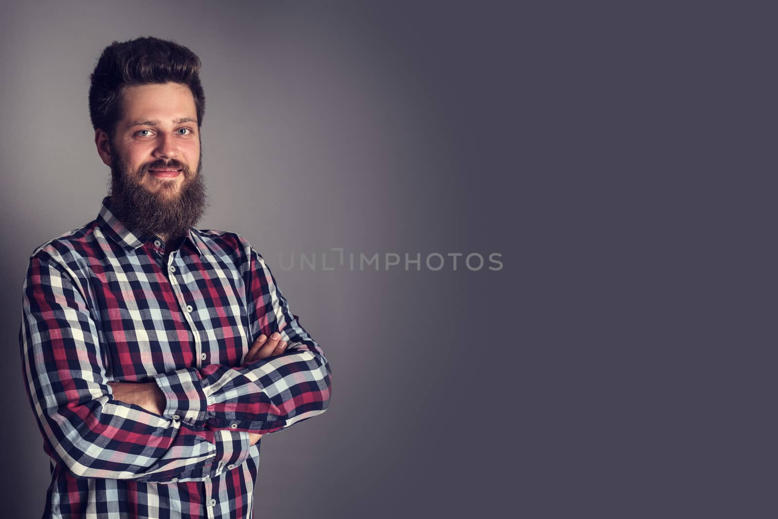 Smiling bearded man in checked shirt, portrait, studio shot on gray background