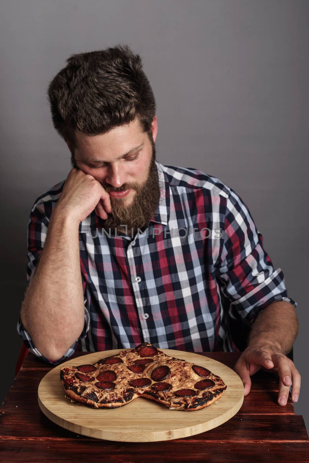 Sad man looking at fail burned heart shaped pizza
