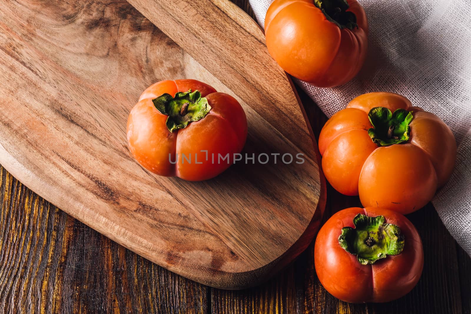 Four Ripe and Sweet Persimmons on Cutting Board