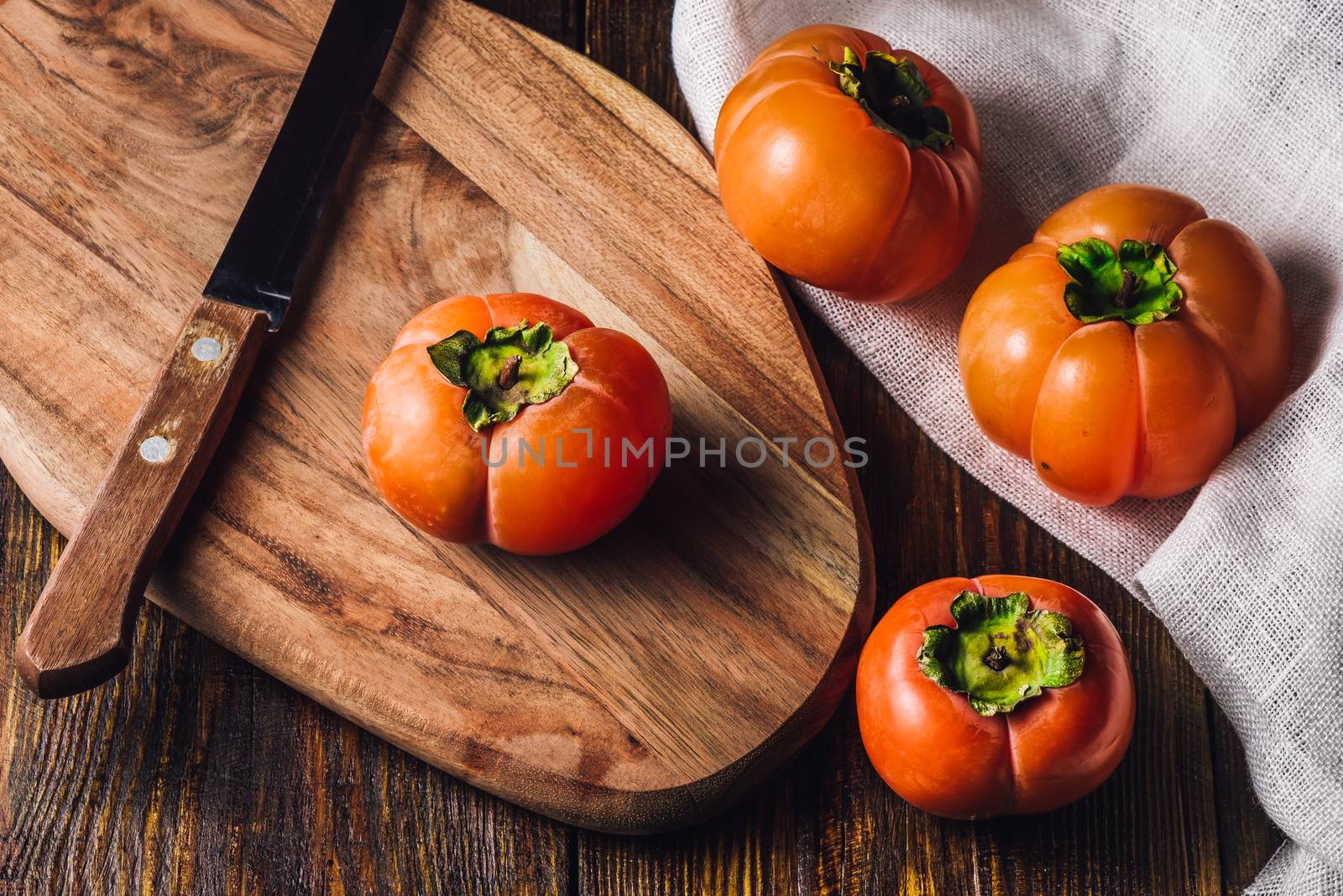 Persimmons with Knife on Wooden Cutting Board