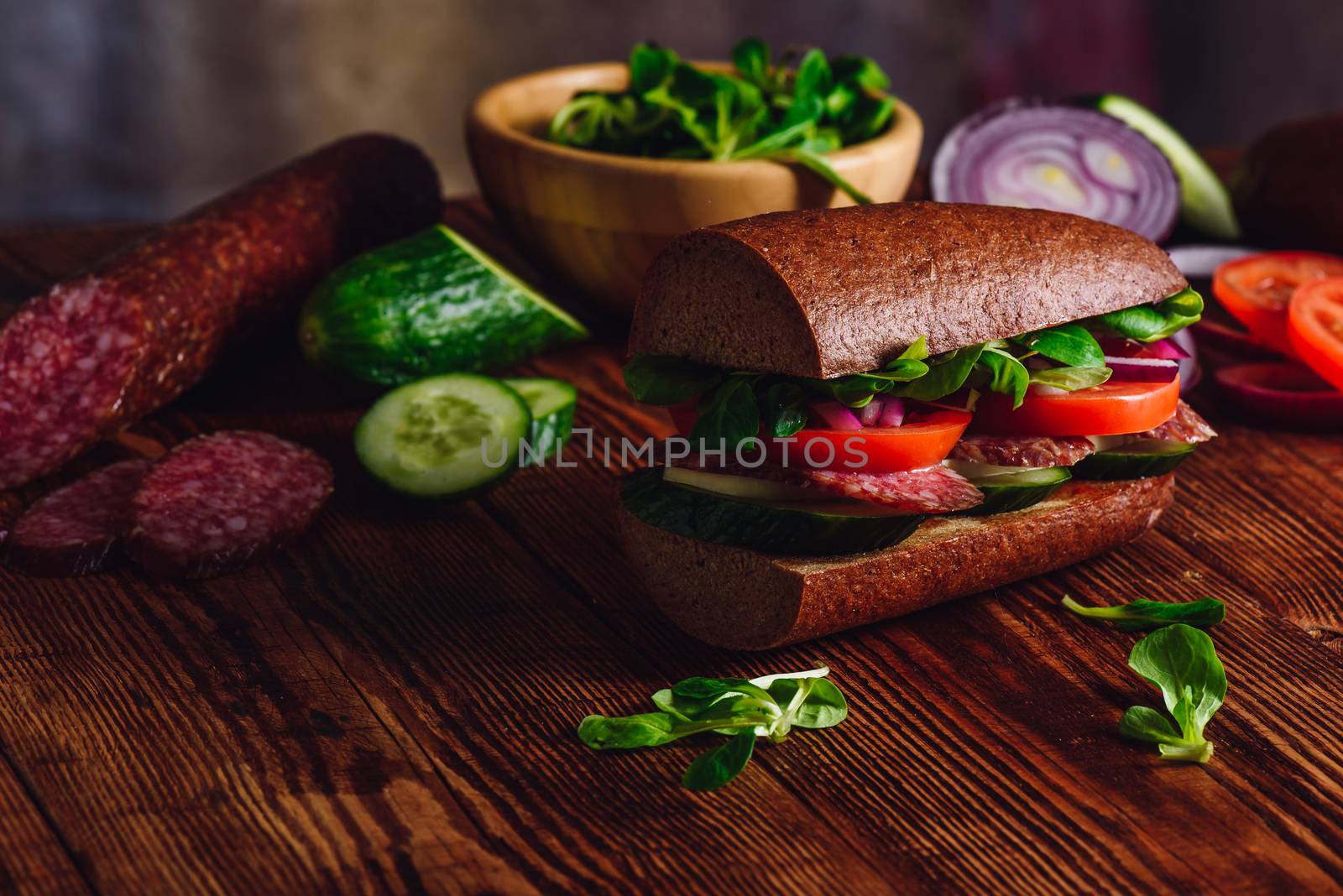 Sandwich with Salami and Fresh Vegetables on Wooden Table