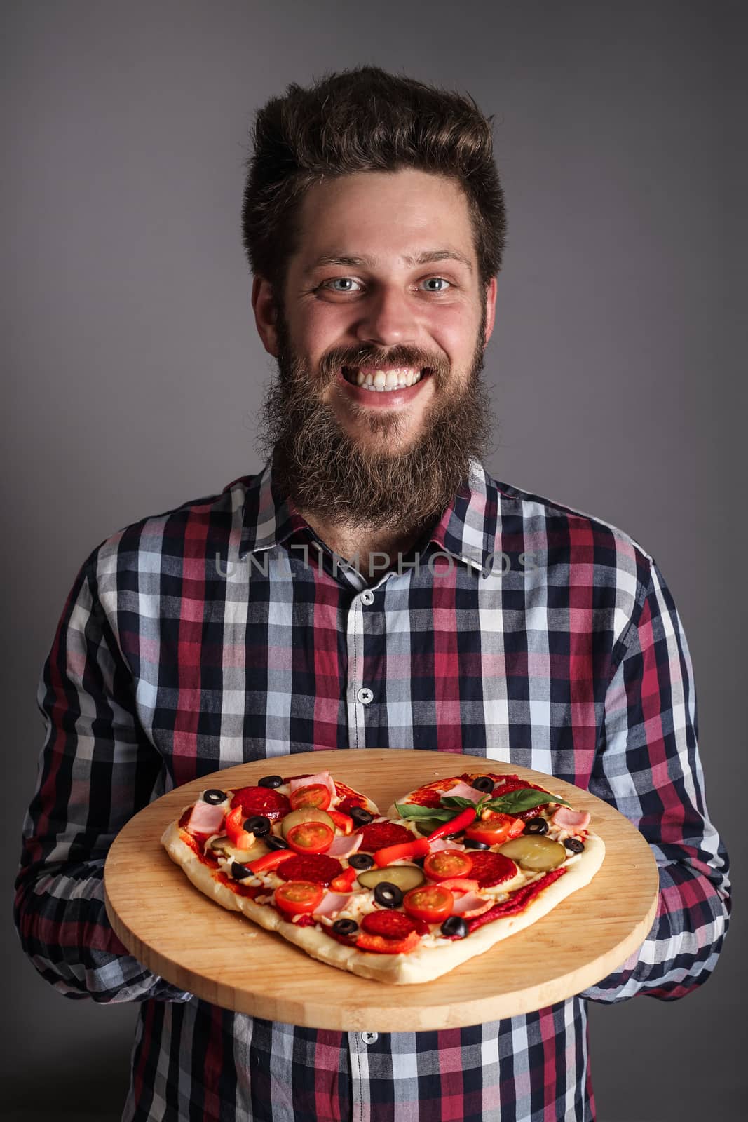 Happy smiling man holding home made heart shaped pizza