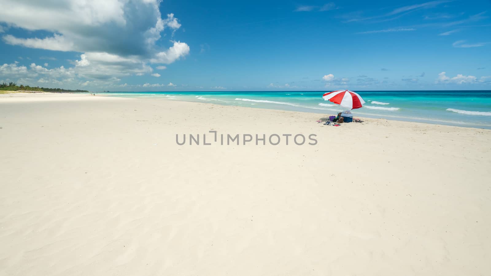 Nice  beach of Varadero during a sunny day, fine white sand and turquoise and green Caribbean sea,on the right one red parasol,Cuba.concept  photo,copy space.