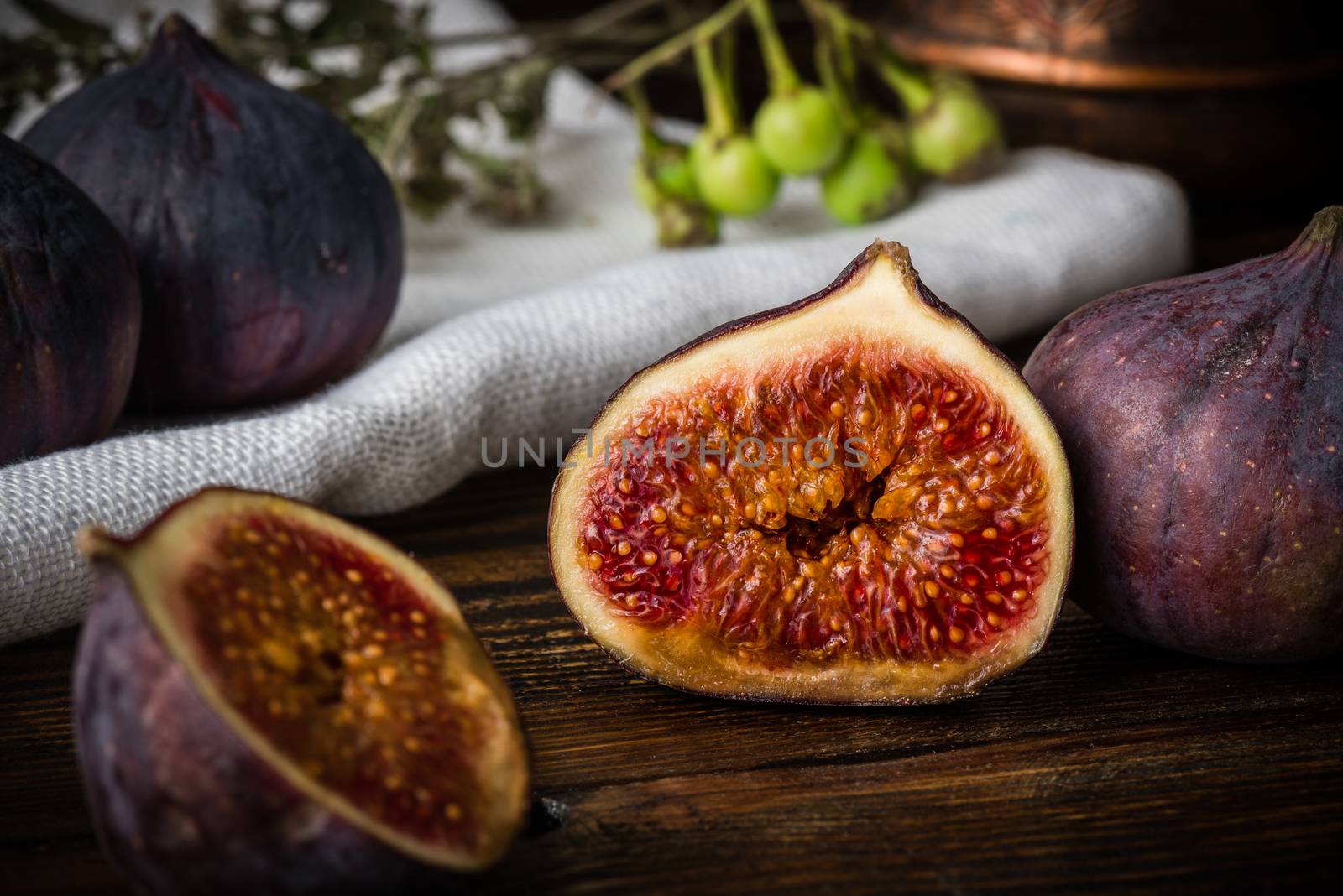 Half ripe and juicy fig lying on rustic table by Seva_blsv